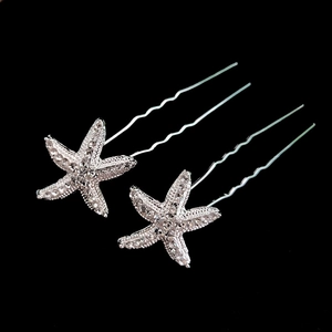 Macro detail of two silver starfish U-shaped hair pins with sparkling rhinestones on black