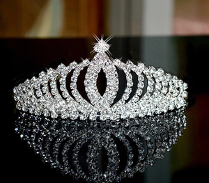 Macro detail of silver bridal crown with sparkling rhinestones on black mirror background