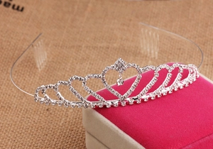 Detail of silver rhinestone crown headband featuring heart-shaped frame and drop pendant