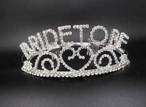 Detail of silver rhinestone bridal tiara featuring heart pattern and Bride To Be lettering
