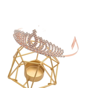 Elegant rose gold tiara with white rhinestones on a minimalist golden display stand