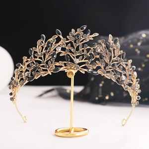 Detail of vintage gold tiara with black crystals and intricate leaf design on stand