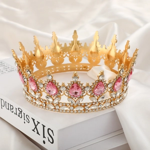 Exquisite gold bridal crown with pink teardrop gemstones on elegant white silk fabric