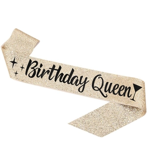 Detail of golden glitter sash with black Birthday Queen lettering and star icons