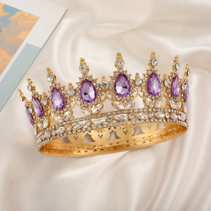 Close-up of golden bridal crown with purple teardrop crystals on white silk