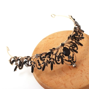 Détail de la couronne baroque avec pierres noires sur un support en bois clair