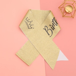 Détail macro de l'écharpe Birthday Queen avec texture pailletée dorée et motif couronne