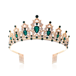 Detail of a gold baroque crown featuring green teardrop gemstones and white crystals