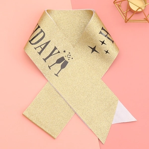 Detail of gold glitter sash with black lettering and champagne glass icons for parties