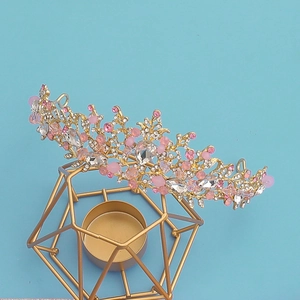 Tiara de mariée dorée élégante avec perles roses et cristaux sur un support doré