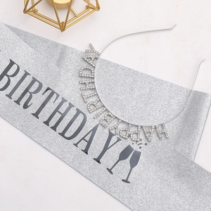 Close-up of silver glitter sash with black lettering and rhinestone headband for birthdays