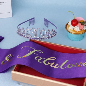 Detailed view of purple 30th birthday tiara and satin sash on a golden gift box
