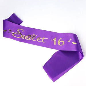 Detail of purple satin Sweet 16 birthday sash with gold lettering and crown graphics