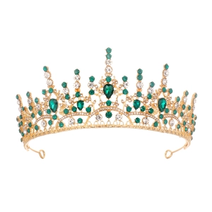 Detailed close-up of emerald green crystals and white rhinestones on golden crown