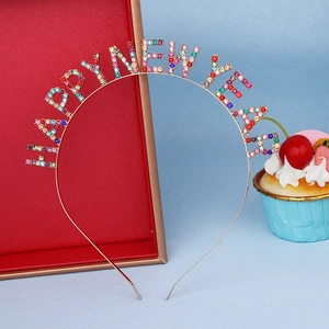 Détail du serre-tête Happy New Year doré avec strass colorés et accessoires de fête festifs