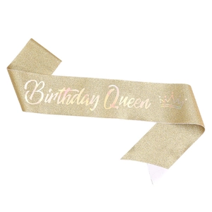 Macro detail of golden glitter sash with Birthday Queen text and crown design