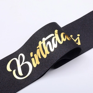 Detail of glittery black birthday sash with gold foil crown and birthday script