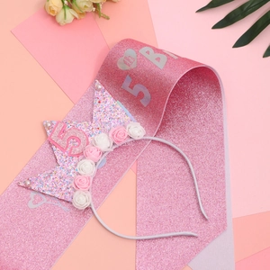 Macro detail of pink glitter sash and flower crown for 5th birthday celebration