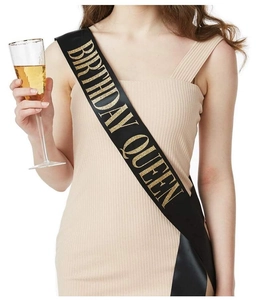 Detail of elegant black satin Birthday Queen sash with golden glitter lettering on a model