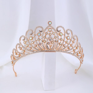 Detail of golden baroque crown with sparkling crystals and AB rhinestones on white fabric