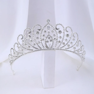 Close-up of a silver rhinestone tiara with intricate scrollwork and pear-shaped crystals