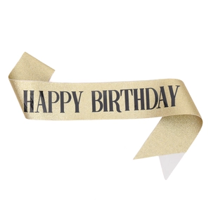 Macro detail of gold glitter Happy Birthday sash with bold black text and swallowtail cut