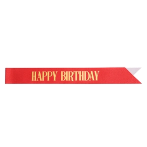 Macro view of a red satin birthday sash with gold Happy Birthday text for party decor
