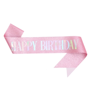 Detail of pink glitter birthday sash featuring holographic Happy Birthday lettering