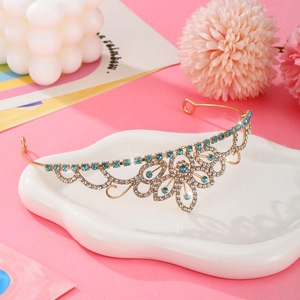 Close-up of golden crown with sky blue rhinestones on a decorative pink background