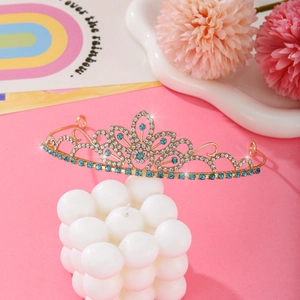 Golden princess crown with sparkling blue crystals and clear rhinestones on pink decor