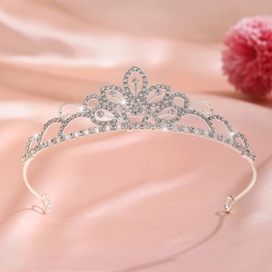 Detail of silver crown headband with sparkling rhinestones on pink satin fabric background