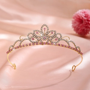 Close-up of golden floral crown with pink crystals on soft silk fabric background