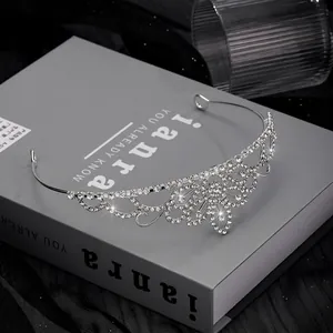Elegant silver tiara with clear crystals and heart floral patterns on a dark background