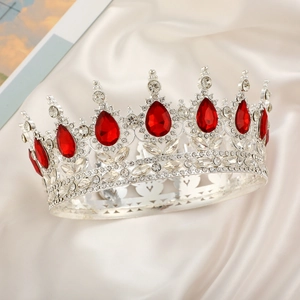 Detail shot of a silver crown with red teardrop gemstones and crystals on silk fabric