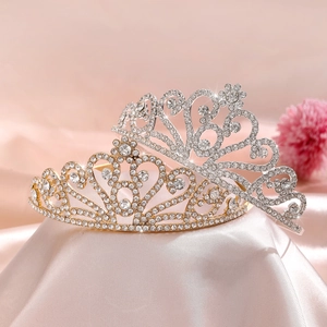 Elegant gold and silver heart tiaras with sparkling crystals on pink silk background