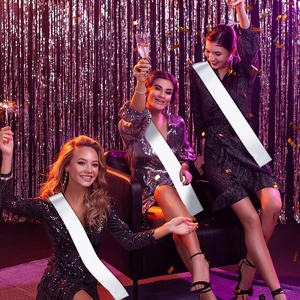 Trois femmes portant des écharpes en satin blanc dans une scène de fête avec fond violet