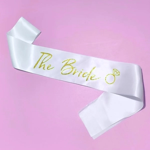 Détail de l'écharpe en satin blanc avec lettrage The Bride doré pour fête de mariage