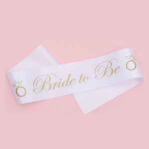 Détail de l'écharpe de mariée en satin blanc avec texte doré Bride to Be et bagues