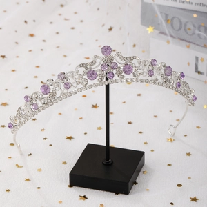 Detailed macro of silver tiara with purple and clear crystals on a minimalist stand