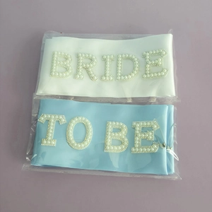 Detailed view of white and blue satin bridal sashes with pearl and rhinestone Bride lettering