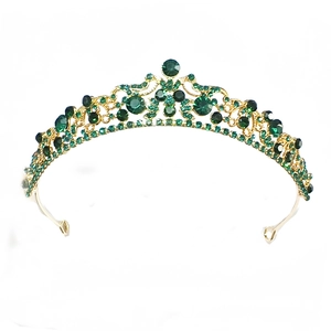 Macro view of vintage gold bridal crown featuring dark green rhinestones and floral patterns