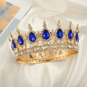 Detailed close-up of golden bridal tiara with pear-cut blue crystals on beige silk fabric