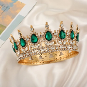 Detail of a gold bridal crown with green teardrop gems and crystals on white silk fabric