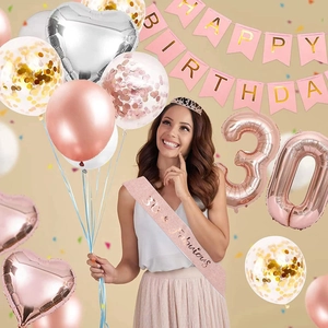 Close-up of 30th birthday set with rose gold balloons, pink banner, sash, and silver crown