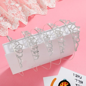 Détail de cinq diadèmes argentés avec strass pour filles sur un fond rose doux