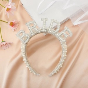Close-up of pearl bridal headband with BRIDE lettering on elegant pink silk background