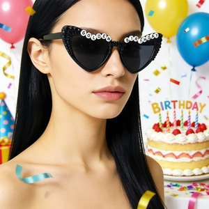 Close-up of heart-shaped sunglasses with GOLDEN BIRTHDAY bead letters and party cake