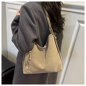Vue latérale du sac hobo beige avec détail zip en métal et bandoulière sur le modèle