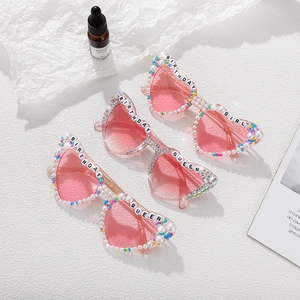 Flat lay of heart-shaped party sunglasses with pearls and Birthday Queen lettering