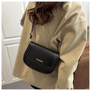 Detailed view of black leather crossbody bag with golden FASHION text on female model
